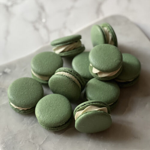 marble counter with tons of basil macarons stacked on top of each other