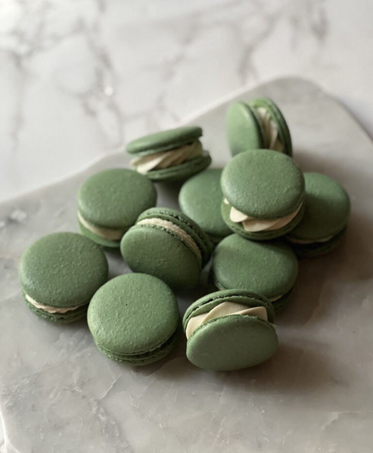 marble counter with tons of basil macarons stacked on top of each other