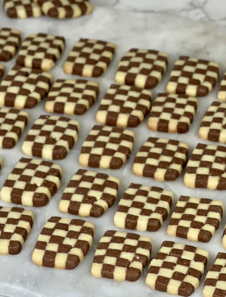 checkerboard cookies on baking sheet on table raw cookie dough