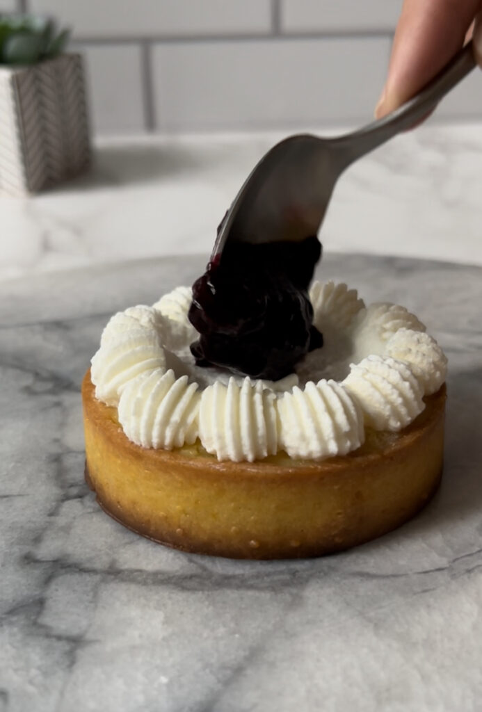 blueberry compote being poured in center of a tart