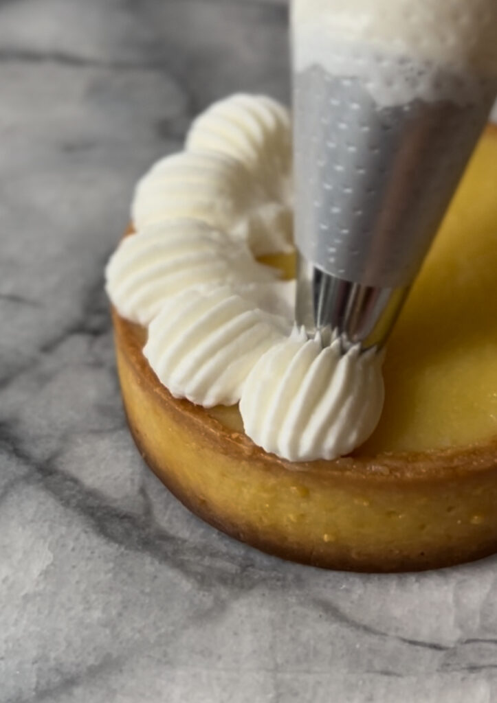 piping chantilly cream on a lemon tart