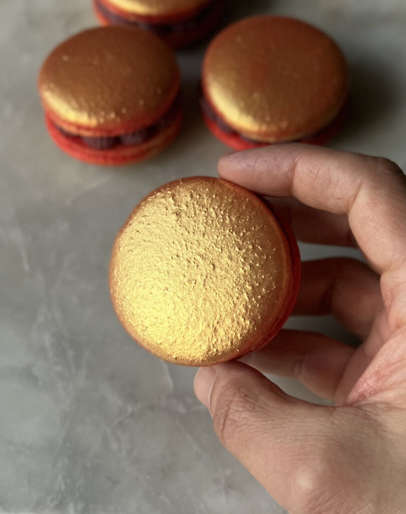 gold topped ruby macaron in hand 