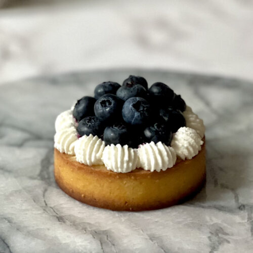 lemon blueberry tart that is on a marble serving tray on counter