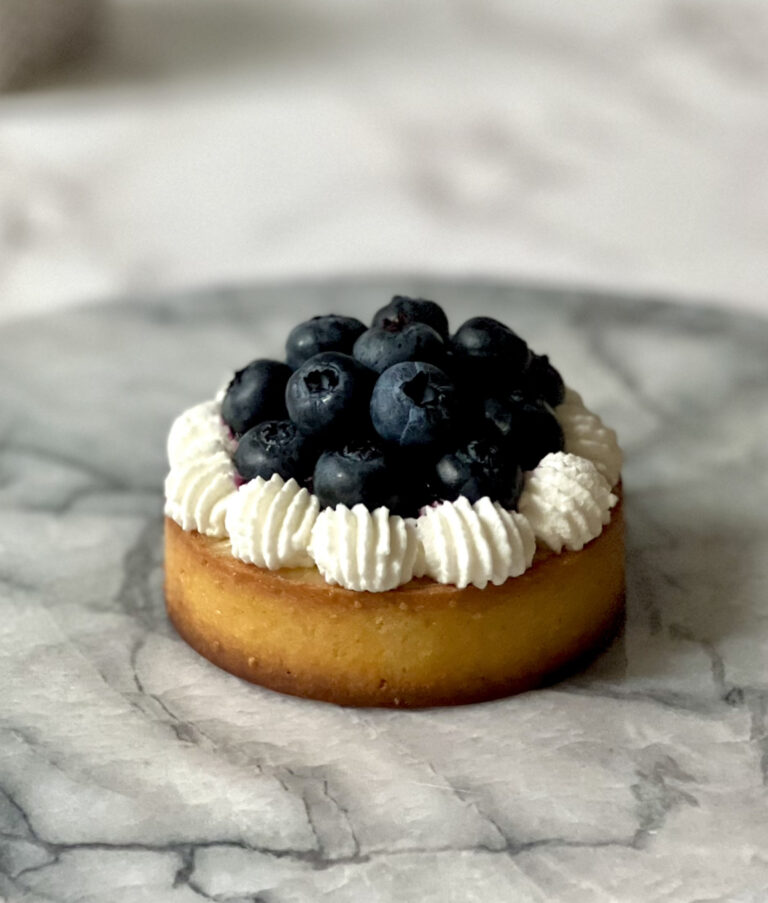 lemon blueberry tart that is on a marble serving tray on counter