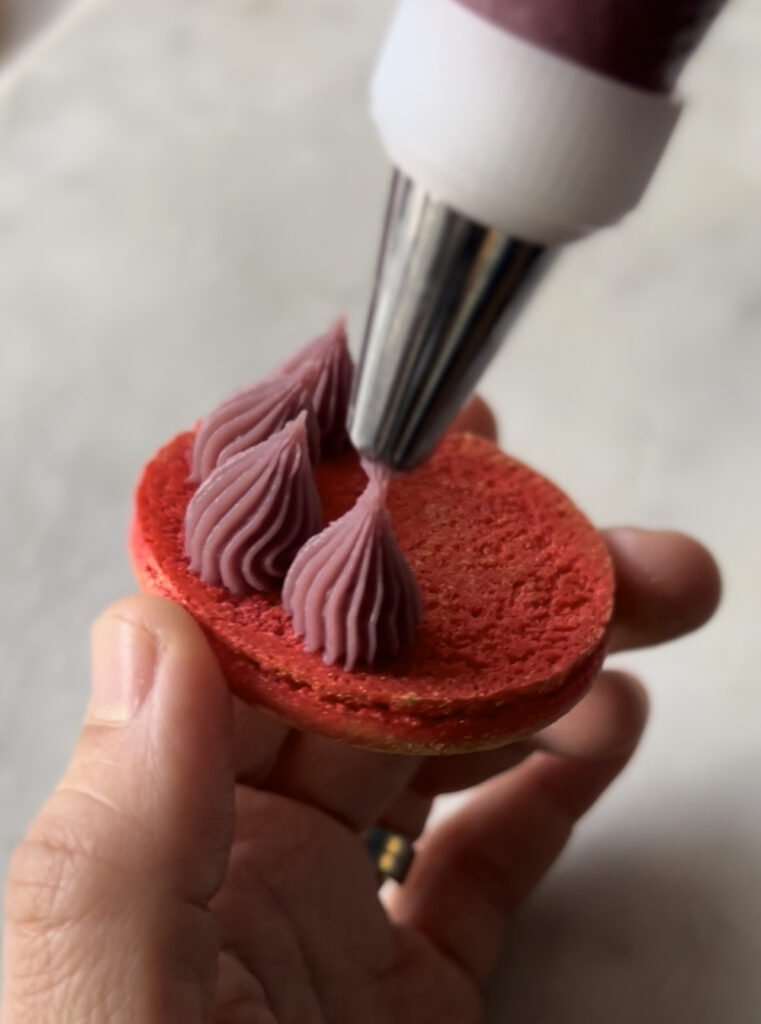 piping ruby ganache in a macaron shell 