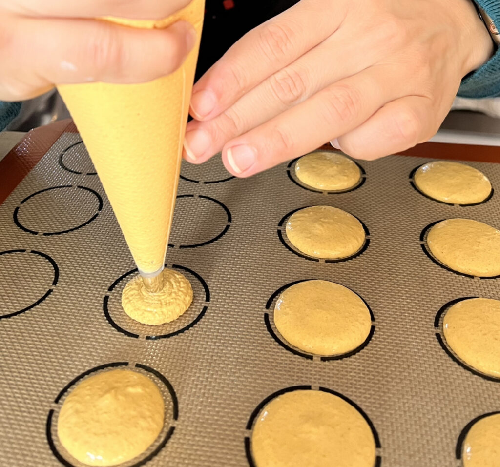 piping macarons on a silicone baking mat