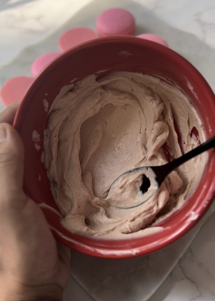 raspberry buttercream in a red bowl with spoon in bowl 