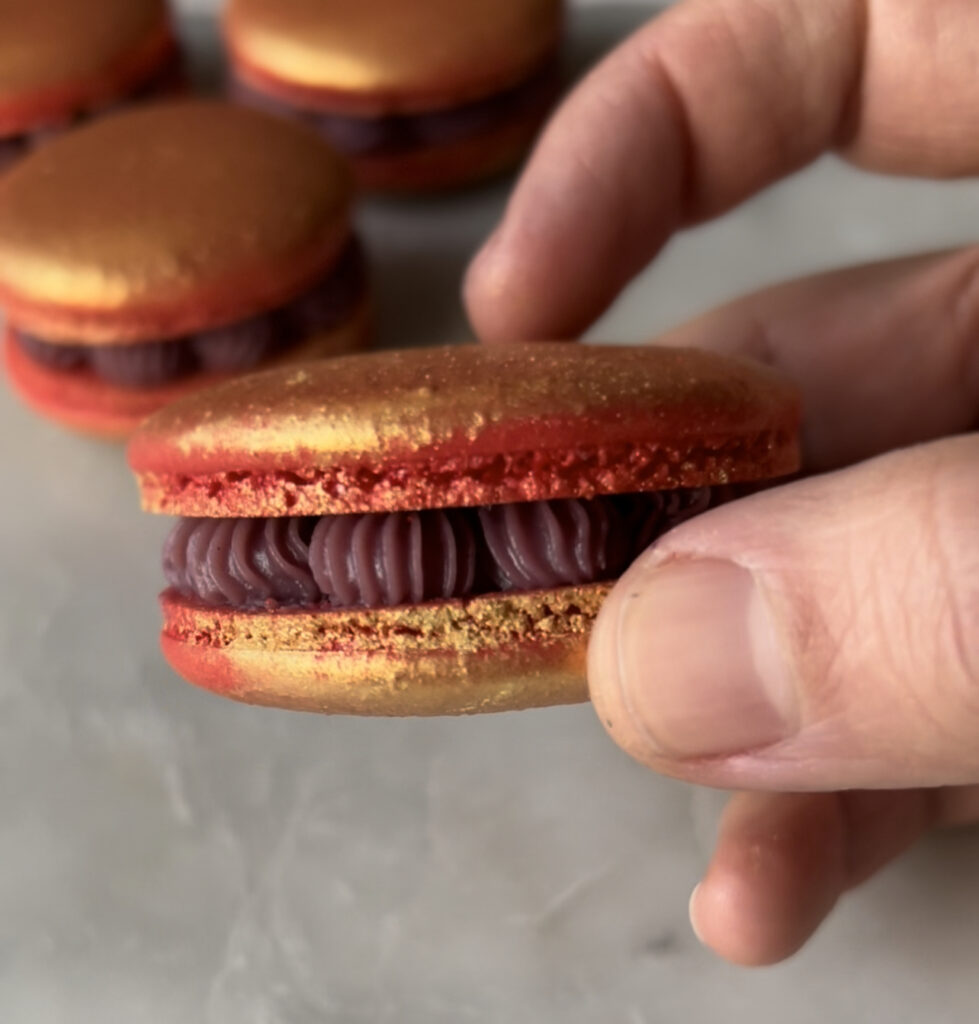 Ruby ganache macaron being held in a hand 