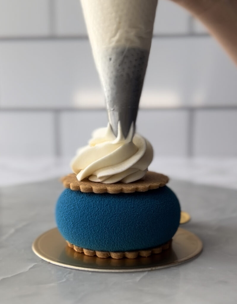 piping whipped ganache on to a blue pastry