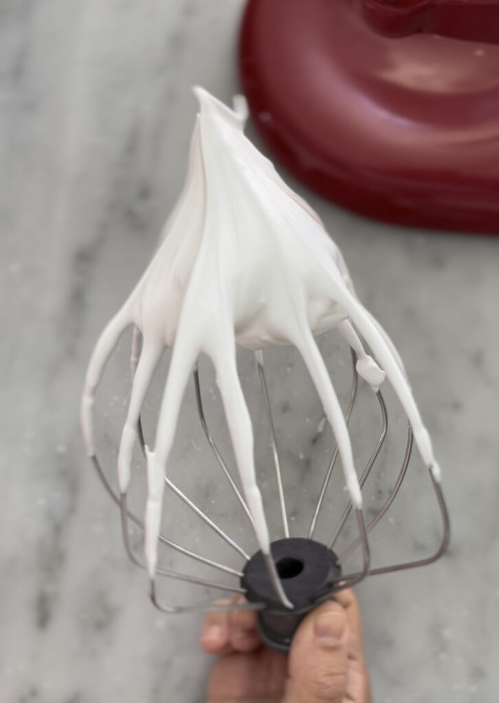 meringue on a whisk being held in hand 